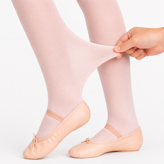 A close-up of a person's legs wearing pale pink tights and ballet flats, with a hand stretching the sheer fabric of the tights to demonstrate elasticity, against a clean white background.
